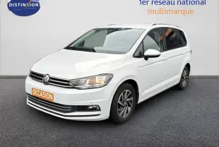 Volkswagen Touran blanc en 3/4 avant droit avec jantes alliage et feux allumés sur fond neutre.
