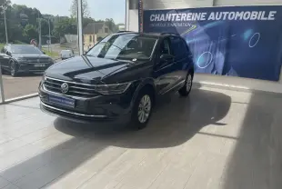 Volkswagen Tiguan noir 2021 en 3/4 avant droit dans showroom avec bannière Chantereine Automobile en arrière-plan.