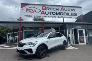 Vue 3/4 avant droite d'un Renault Arkana blanc perle avec toit noir, stationné devant un garage Brech Auray Automobiles.