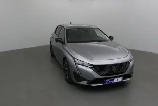 Peugeot 308 gris Artense vue 3/4 avant gauche dans un studio, avec calandre noire et feux LED distinctifs.