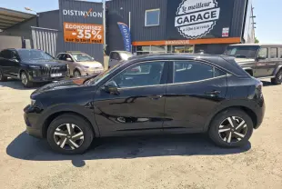 Opel Mokka noir vue de profil côté gauche, avec jantes bicolores et toit couleur carrosserie, stationné devant un garage.