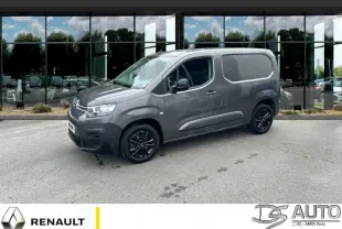 Vue 3/4 avant droit d'un Citroën Berlingo 2023 gris foncé avec jantes noires, stationné devant une vitrine réfléchissante.