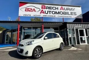 Nissan Micra blanc perle vue 3/4 avant droit, garée devant un garage Brech Auray Automobiles par temps clair.