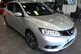 Nissan Pulsar gris glacier vue 3/4 avant droit en showroom, mettant en valeur ses phares et jantes alliage.