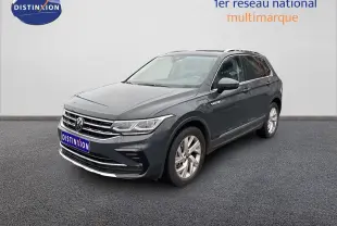 Volkswagen Tiguan 1.4 E-Hybrid gris lunaire en 3/4 avant droit sur sol gris devant un mur blanc.