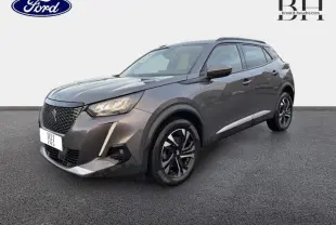 Peugeot 2008 gris Artense vue 3/4 avant droit, avec jantes alu et barres de toit visibles.