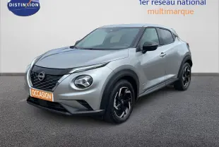 Nissan Juke Hybrid gris perle métal en 3/4 avant droit, avec jantes noires et calandre noire distinctive.
