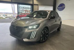 Peugeot 208 gris Artense vue 3/4 avant droit, avec calandre noire et feux LED allumés en showroom.