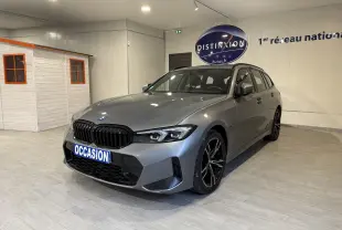BMW Série 3 Touring G21 gris en 3/4 avant droit avec calandre noire et jantes sport en showroom intérieur.
