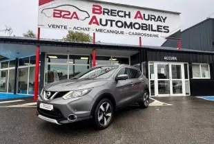 Nissan Qashqai gris Squale en 3/4 avant droit devant un garage Brech Auray Automobiles par temps couvert.