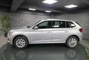 Vue de profil côté gauche d’un Skoda Kamiq gris métallisé 2023 en intérieur avec jantes alliage 16 pouces.