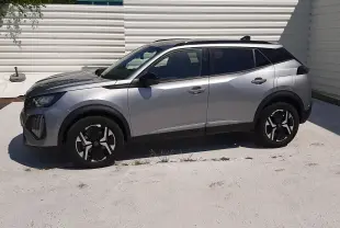 Peugeot 2008 gris Artense vue de profil côté gauche, barres de toit noires et jantes distinctives.