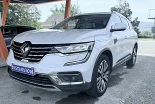 Renault Koleos blanc en 3/4 avant droit sous abri, avec calandre chromée et jantes alliage distinctives.