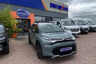 Citroën C3 Aircross gris kaki avec toit blanc, vue 3/4 avant, devant un concessionnaire Distinxion.