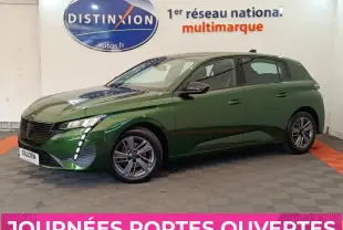 Peugeot 308 vert vue 3/4 avant droit, avec feux LED verticaux et jantes alliage, en intérieur showroom.