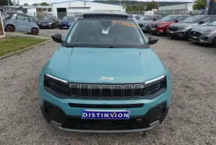 Vue avant d'un Jeep Avenger bleu métallisé 2024 avec calandre noire et plaque Distinxion sur parking.