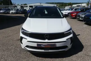Vue avant d'un Opel Grandland blanc métallisé avec calandre noire brillante et phares LED, sur un parking extérieur.