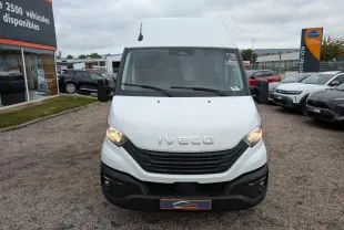 Vue avant d'un utilitaire Iveco Daily blanc avec calandre noire et phares allumés sur un parking.
