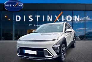 Hyundai Kona gris 2025 en 3/4 avant droit avec calandre lisse et phares LED distinctifs devant showroom Distinxion.