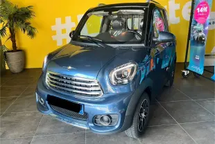 Vue 3/4 avant d'une voiture électrique TODAY SUNSHINE M1 bleu avec phares LED et calandre chromée en intérieur showroom.