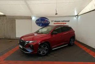 Hyundai Tucson rouge vue 3/4 avant droit en intérieur, avec jantes alliage noires et toit noir.