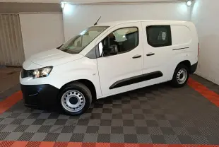 Peugeot Partner blanc en vue de profil côté gauche, avec cloison grillagée visible à l'arrière.