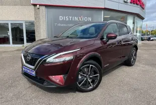Vue 3/4 avant d'un Nissan Qashqai e-POWER 2023 Rouge Passion avec jantes alliage 19 pouces devant un concessionnaire.