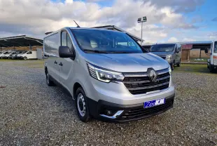 Renault Trafic Fourgon gris Highland en 3/4 avant droit, avec calandre noire et feux LED allumés.