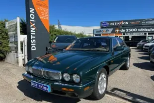 Jaguar Sovereign 3.2 V8 vert vue 3/4 avant droit sur parking devant concession Distinxion.