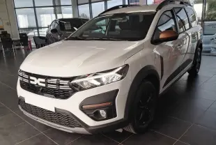 Vue 3/4 avant d'un Dacia Jogger blanc avec détails noirs et rétroviseurs cuivrés, en showroom intérieur.