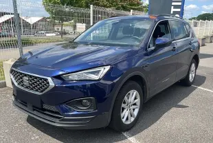 SEAT Tarraco bleu métal vu en 3/4 avant droit, mettant en valeur sa calandre distinctive et ses jantes argentées.