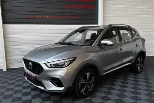 MG ZS gris clair vu en 3/4 avant droit dans un showroom avec jantes noires et toit ouvrant.