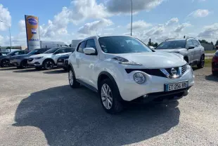 Nissan Juke blanc en 3/4 avant droit sur parking, avec jantes alliage 17 pouces sport visibles.