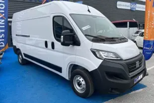 Fiat Ducato Fourgon blanc vu en 3/4 avant droit, avec calandre noire et rétroviseurs noirs sur parking commercial.