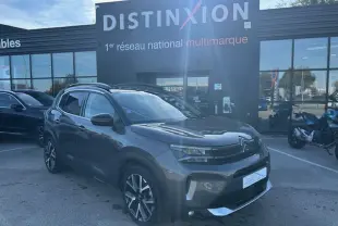 Citroën C5 Aircross gris platinium en 3/4 avant droit, avec barres de toit et jantes alliage visibles.