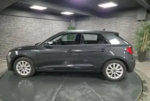 Profil côté gauche d'une Audi A1 Sportback gris Manhattan 2024 avec jantes argentées en intérieur showroom.
