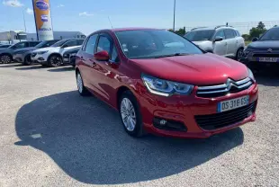 Citroën C4 rouge métallisé vue 3/4 avant droit sur parking avec projecteurs antibrouillard et calandre chromée.