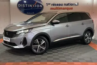 Peugeot 5008 gris clair en vue 3/4 avant droit, avec jantes alliage et phares LED allumés en intérieur showroom.
