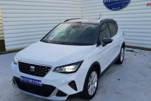 SEAT Arona blanc Nevada avec toit gris, vue 3/4 avant droit, calandre noire et feux LED allumés.