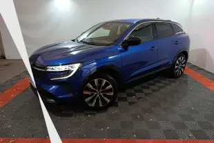 Renault Austral Techno bleu en 3/4 avant droit, avec jantes alliage et phares LED allumés dans un studio.