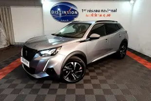 Peugeot 2008 gris clair en 3/4 avant droit, avec jantes noires et toit noir, dans un showroom intérieur.