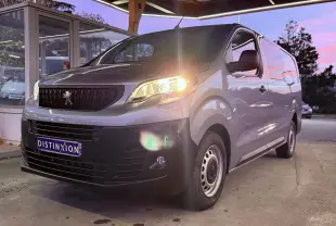 Vue 3/4 avant droit d'un Peugeot Expert Cabine Approfondie gris Artense métal avec phare allumé sous un abri.