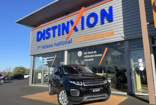 Range Rover Evoque noir en 3/4 avant droit devant un showroom avec enseigne Distinxion visible.