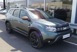 Dacia Duster 2024 vert cèdre métallisé en 3/4 avant droit, avec jantes noires et coques de rétroviseur bronze.