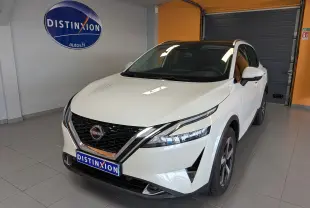 Nissan Qashqai blanc en 3/4 avant droit, toit noir et calandre chromée dans un showroom intérieur.