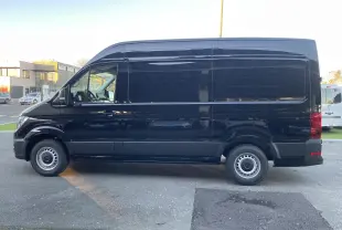 Profil latéral gauche d'un Volkswagen Crafter Van noir intense 2025, version longue et haute, sans fenêtres latérales arrière.