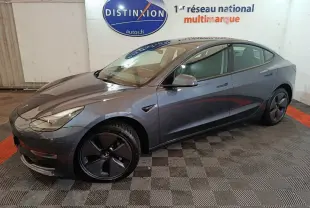Tesla Model 3 Grande Autonomie gris foncé vue de côté droit en intérieur avec jantes noires et logo visible.