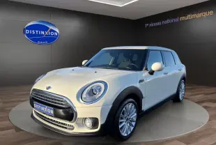 Vue 3/4 avant droit d'une MINI Clubman blanche exposée en showroom avec jantes alliage et phares ronds LED.