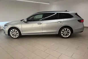 Vue de profil côté gauche d'une Skoda Superb Combi gris argent avec jantes alliage 18 pouces en intérieur showroom.