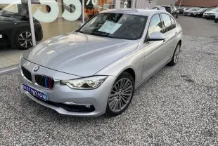 BMW Série 3 F30 gris clair vue 3/4 avant droit avec calandre ornée de liserés tricolores M